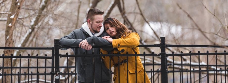 A couple leans on a fence