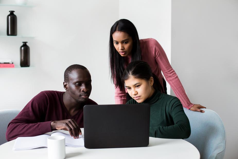 3 people crowd around a laptop